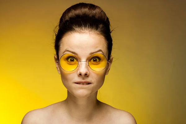 Sarı gözlüklü, çıplak omuzlu güzel bir kadın. Duyguları çekici görünüyor. — Stok fotoğraf