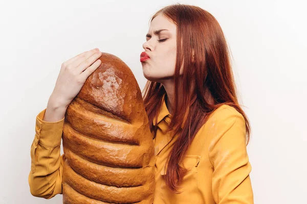 Mulher beijando pão no fundo claro e amarelo produto de farinha camisa vista cortada — Fotografia de Stock