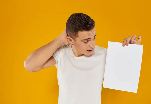 Kerel met een wit velletje papier op een gele achtergrond close-up cropped view — Stockfoto