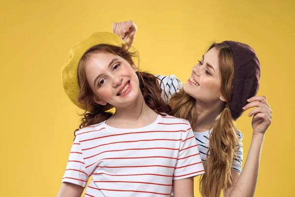 帽子ストライプのTシャツの陽気な姉妹はライフスタイルを楽しむ黄色の背景家族 — ストック写真
