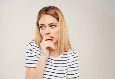 Güzel sarışın kadın, elleri bej arka planda kesilmiş portrede el kol hareketi yapıyor.