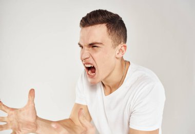 Beyaz tişörtlü duygusal bir adam ellerini arka planda açık bir modele koyar. Stres gerginliği.