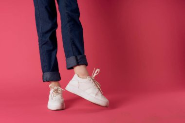 Kadın ayakları beyaz spor ayakkabılar sokak moda stüdyosu pembe arka plan