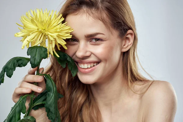 Portrait d'une belle femme avec une fleur jaune sur un fond clair charmant sourire modèle cheveux rouges — Photo