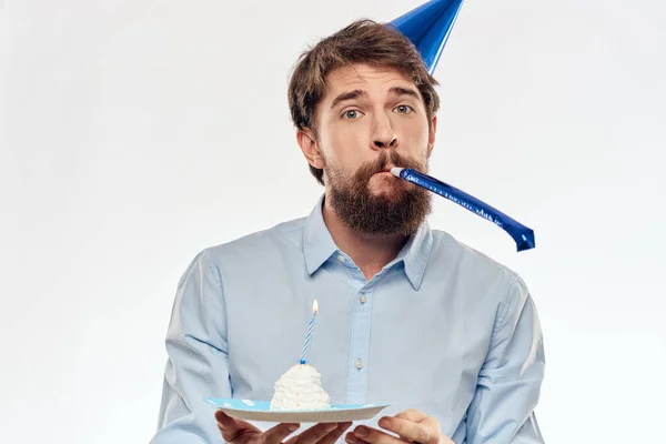 A man with a cake plate and in a blue shirt on a light background birthday party corporate cap