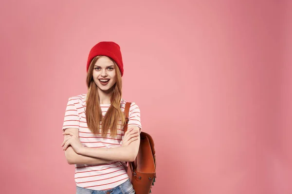 Modieuze glamoureuze vrouw in rode hoed rugzak student hipster roze achtergrond — Stockfoto