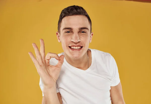 Homem mostra gestos positivos com as mãos divertido fundo amarelo vista cortada — Fotografia de Stock