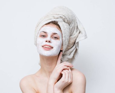 Yüzünde siyah noktalar ve kafasında havlu olan temiz cilt kozmetoloji maskesi olan bir kadın.