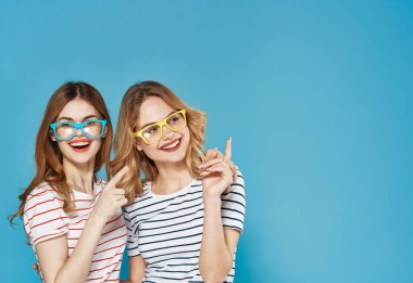 Çok renkli gözlüklü asılmış kız kardeşler çizgili tişörtler. Kopya Boşluğu ile kesilmiş duygular.