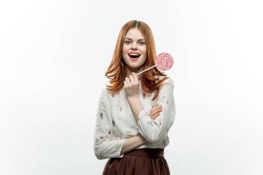 Dişlerinde lolipop tutan kadın arka planda hafif neşe