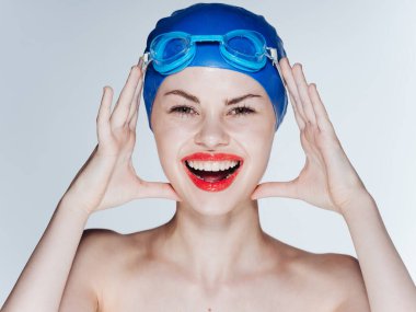 Mavi yüzme şapkası takan duygusal bir kadın arka planda kırışık bir görünüm sergiliyor.