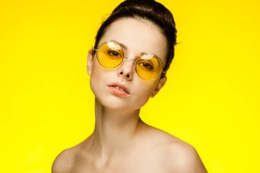 Esmer, çıplak omuzlu çekici, sarı arka planda.