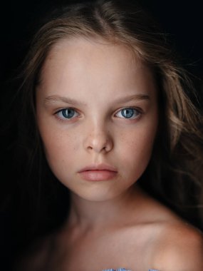 Esmer arka planda, çıplak omuzlu güzel bir kızın portresi.