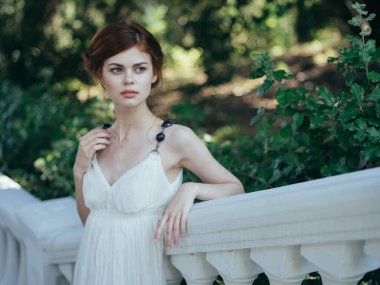 Beyaz elbiseli kadın cazibeli taze hava yeşil yapraklı yürüyüş modeli