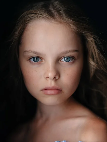 Портрет красивой маленькой девочки на тёмном фоне в сарафане, голые плечи — стоковое фото