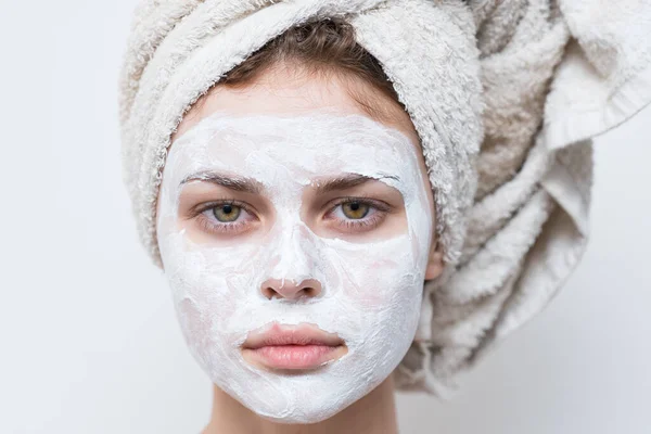 Kobieta z ręcznikiem na głowie i kremem nawilżającym na twarzy — Zdjęcie stockowe