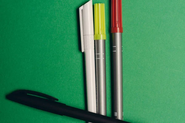 Canetas multicoloridas em um fundo verde material de escritório artigos de papelaria — Fotografia de Stock
