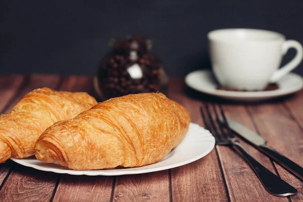 Croissanter vita tallrikar på bordet köksutrustning en kopp — Stockfoto