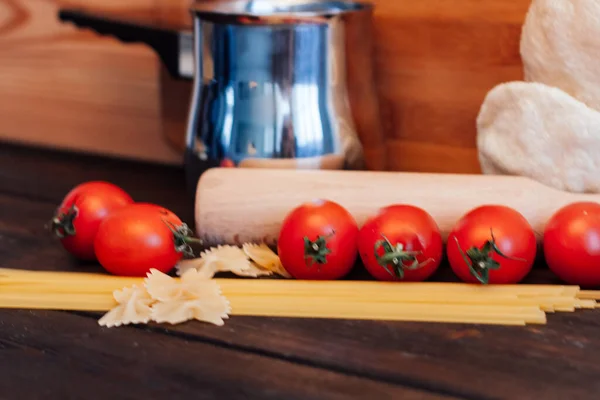 Pasta su un tavolo di legno pomodorini da cucina pentole — Foto Stock