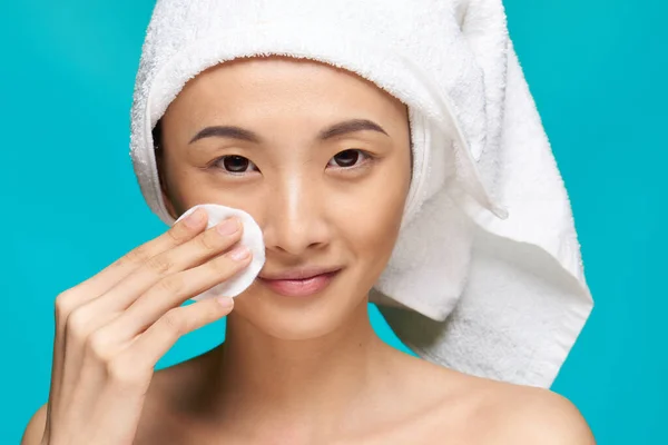 Bella donna asciugandosi il viso con un batuffolo di cotone pelle pulita salute sfondo blu — Foto Stock
