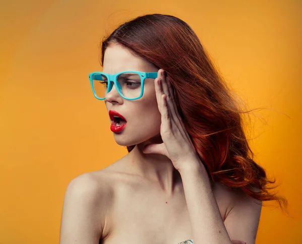 Pretty woman naked shoulders red lips glasses luxury yellow background — Stock Photo, Image