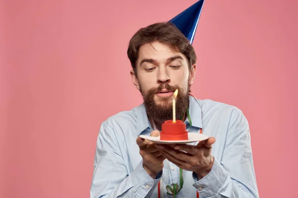 Cumpleaños de un hombre con un pastel y con una vela sobre un fondo rosa — Foto de Stock