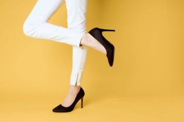 Kadın ayakları siyah ayakkabılar moda stüdyosu sarı arka plan