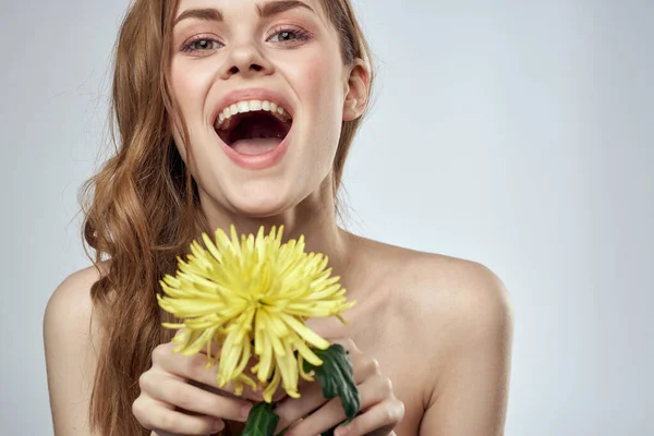 Portrait d'une belle femme avec une fleur jaune sur un fond clair recadré d'espace de copie Modèle — Photo