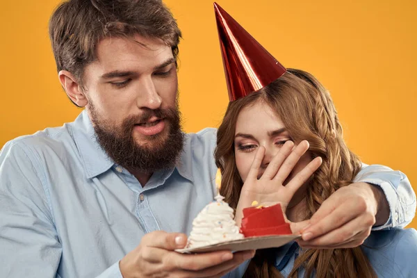 Születésnap party férfi és nő szórakozás sárga háttér sapka ünnep — Stock Fotó