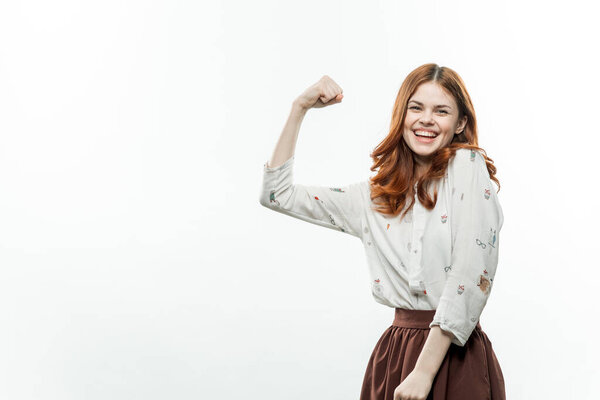 Red-haired woman in a suit gesturing with her hands light background. High quality photo