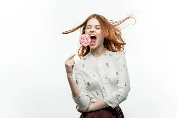Glad rödhårig kvinna med en klubba i händerna känslor öppna munnen sötsaker — Stockfoto