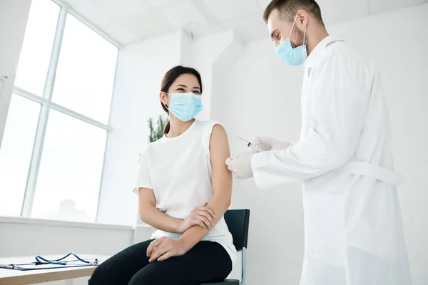 Medico in abito medico e una donna in maschera protettiva covid-19 vaccinazione coronavirus — Foto Stock