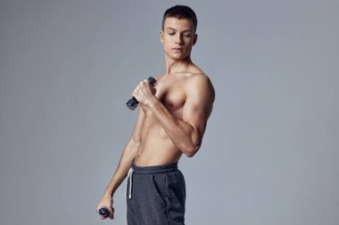 Spor adamı spor salonunun elinde dambıl egzersizi yapıyor.