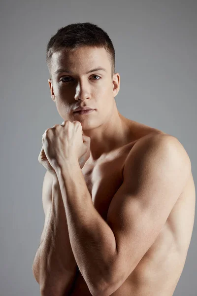 Portrait d'un gars sur un fond gris bras nu muscles bodybuilder — Photo