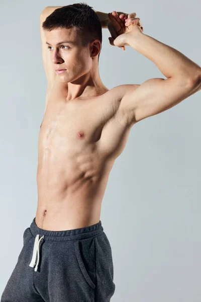 Atleta bonito com torso inflado mantém as mãos atrás de sua cabeça fisiculturista corte vista — Fotografia de Stock
