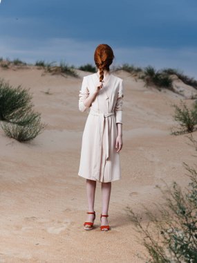 Uzun boylu, kızıl saçlı, yüzünde atkuyruğu olan, kırmızı ayakkabılı bir kadın.