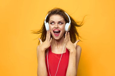 Beyaz kulaklıklı duygusal kadın müzik dinliyor. Eğlenceli yaşam tarzı sarı arka plan.