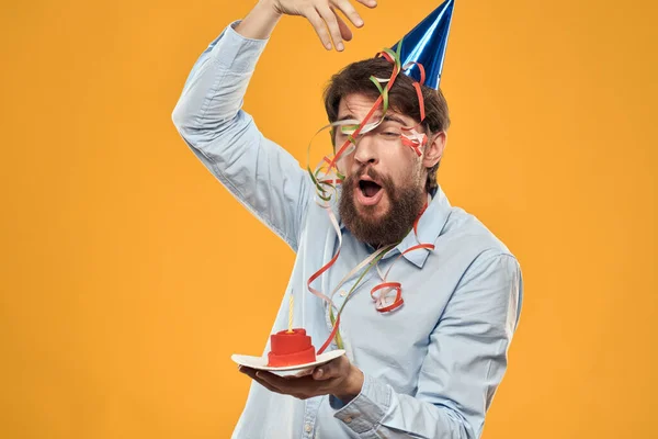 Cheerful man with a cake on a yellow background birthday holidays cap on his head