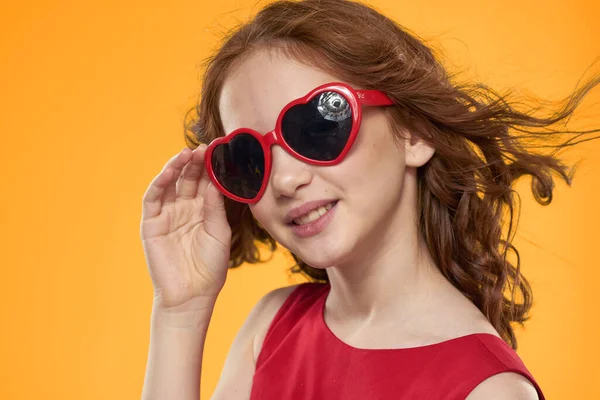 Ragazza in occhiali neri vestito rosso infanzia divertimento giallo sfondo — Foto Stock