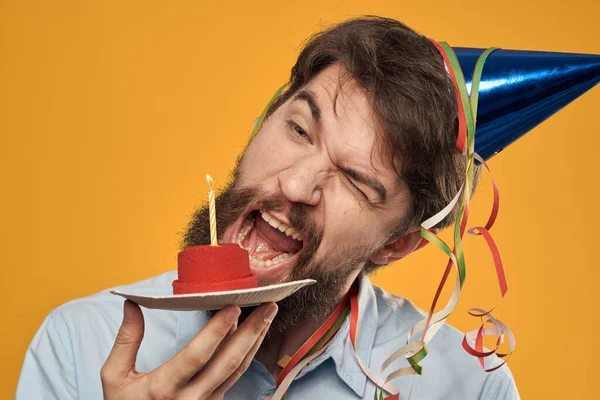 Cumpleaños niño en una gorra con un pastel de cumpleaños en la mano y una vela — Foto de Stock