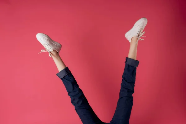 Inverterade kvinnliga ben vita sneakers rörelse gata stil rosa bakgrund — Stockfoto