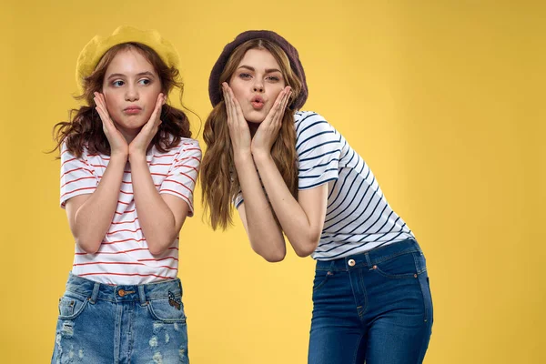 funny mom and daughter wearing hats fashion fun joy family yellow background