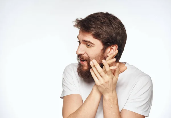 Емоційний чоловік з бородою тримає руки біля свого обличчя на світлому тлі обрізаного вигляду — стокове фото