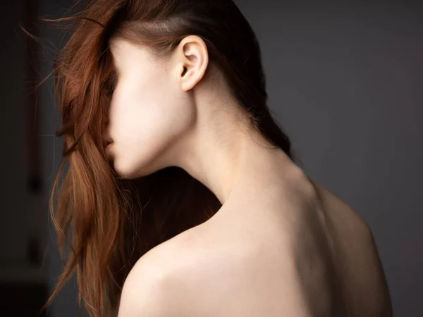 Sexy vrouw met een naakte rug op een grijze achtergrond rood haar terug uitzicht — Stockfoto