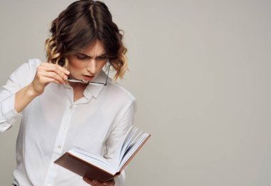 Elinde not defteri olan kadın yüzünde finans gözlüğü taşıyor.