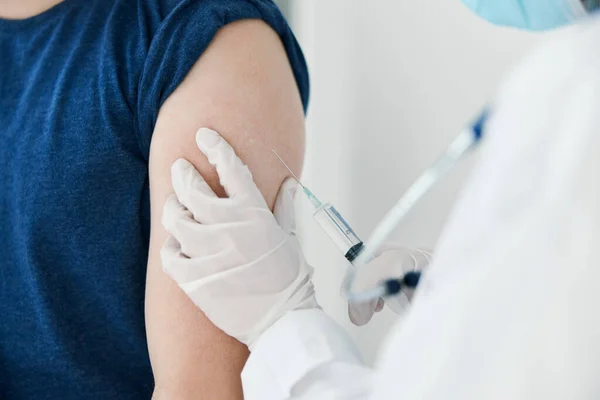 Kobieta lekarz w rękawiczkach ochronnych zastrzyki w ramię mężczyzna w niebieskiej koszulce szczepienia — Zdjęcie stockowe