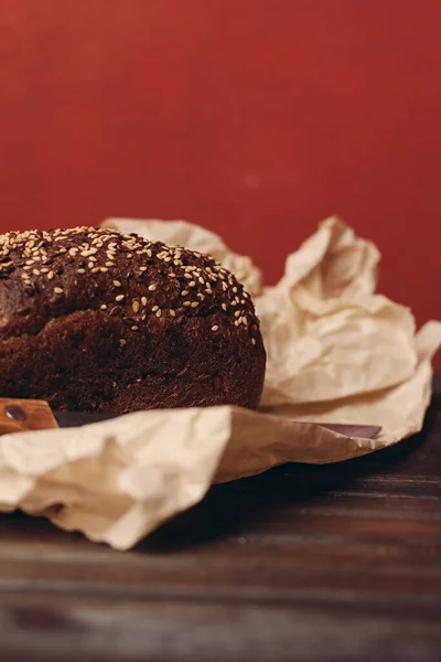 rye bread on paper packaging on a red background and a wooden table with a sharp knife