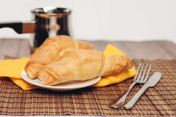 Krispiga färska croissanter på en tallrik på bordet frukost dessert — Stockfoto