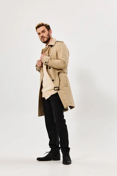 Чоловік в бежевому пальто мода сучасного стилю виглядає осторонь — стокове фото