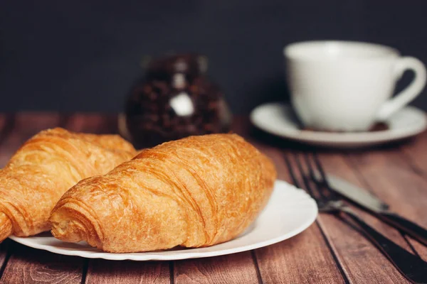 Croissanter vita tallrikar på bordet köksutrustning en kopp kaffe måltid dessert — Stockfoto